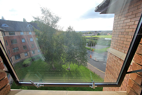 View from window of hall, trees, road and field in distance