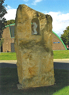 Small statue of lady inset near the top of a block of stone